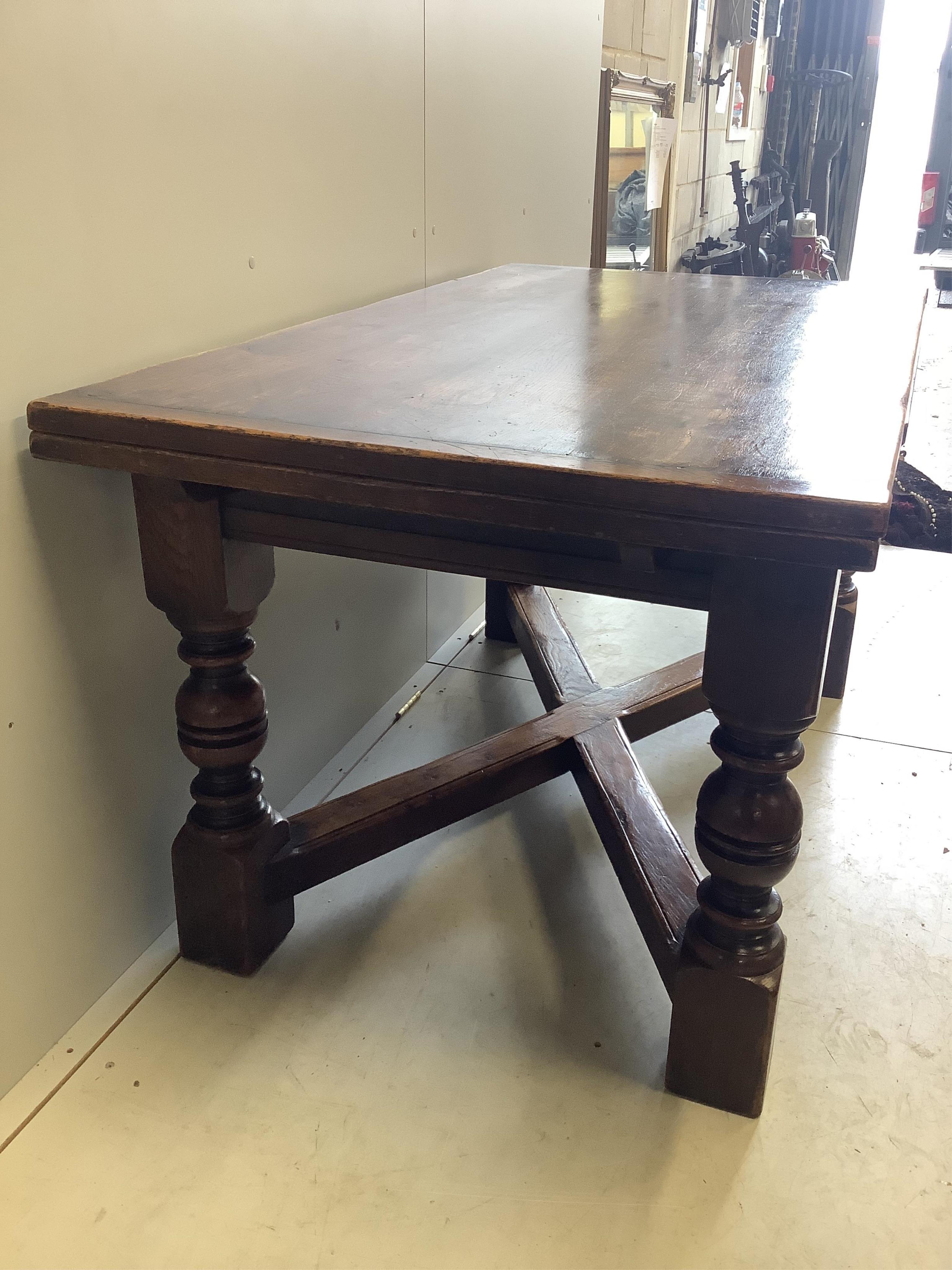 An 18th century style rectangular oak draw leaf refectory dining table, width 244cm extended, depth 85cm, height 79cm together with seven caned oak dining chairs, two with arms. Condition - fair to good